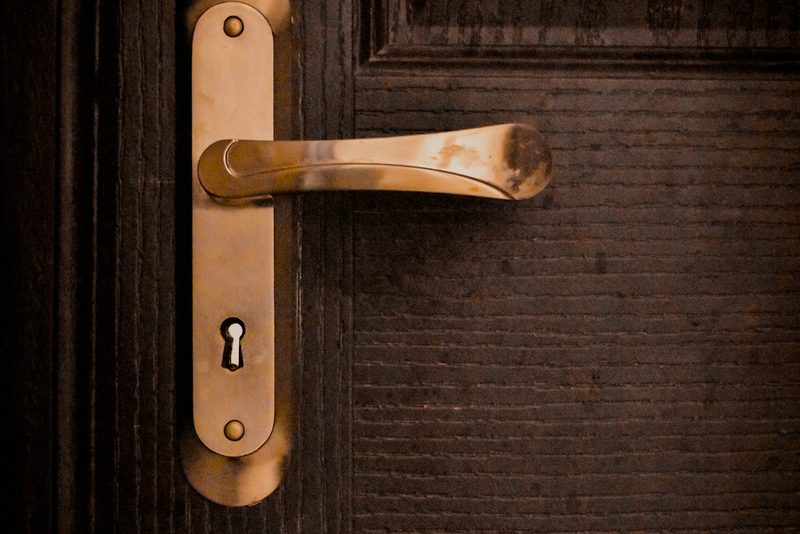 Aged brass lever handle and keyhole on a panelled wooden front door